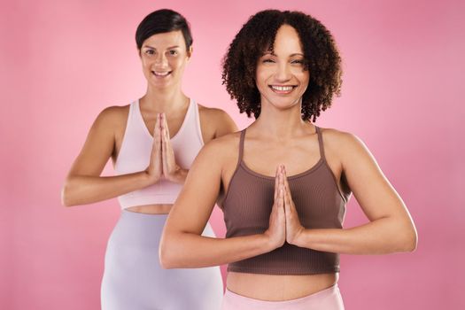 Get your zen on. Cropped portrait of two attractive young female athletes meditating in studio against a pink background.