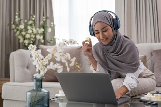 Portrait of beautiful Muslim asian woman wearing headset, communicating online on laptop computer, indoors