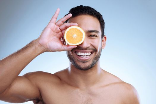 Destroy blemishes with a boost of vitamin C. Studio portrait of a handsome young man posing with an orange against a grey background.