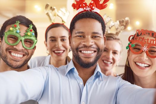 The year is over, now the party begins. Portrait of a group of businesspeople taking selfies together during a Christmas party at work.