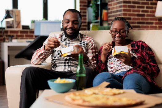 Young couple enjoying noodles meal from takeaway delivery