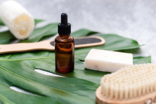 Natural cosmetics for bathing on the background of a palm leaf. Body moisturizing soap, serum and oil, loofah loofah and drainage brush