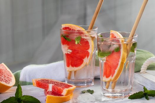 Summer refreshing cocktails with grapefruit slices and mint on a white wooden tray