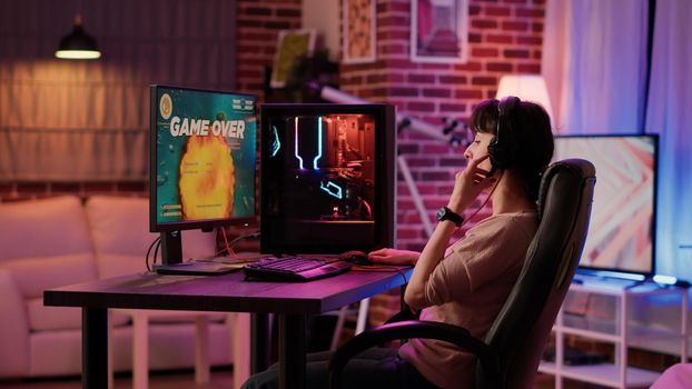 Gamer girl feeling disappointed after losing difficult level in online space shooter on gaming pc