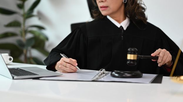 Mature female lawyer preparing contract or agreement document to customer for signing in courtroom legal