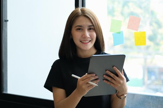 A female company employee uses a tablet and notepad to analyze company budgets.