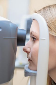 A young girl at the reception at the ophthalmologist checks her eyesight on a special apparatus. Close-up