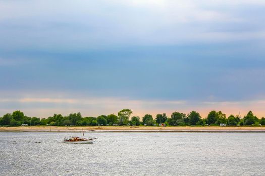 Boats at beautiful wadden sea tidelands coast beach water and dike landscape panorama of the Harrier Sand island in Schwanewede Osterholz Lower Saxony Germany.