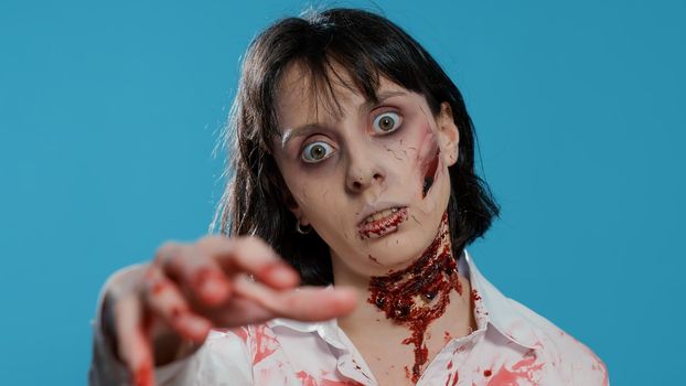 Undead zombie woman with bloody and deep wounds on neck prowling at camera