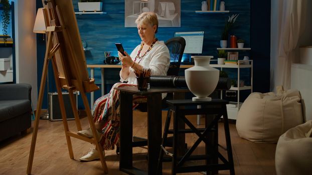 Retired woman drawing authentic vase model on canvas