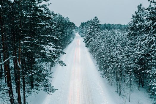 Aerial drone view of snowy winter road in forest