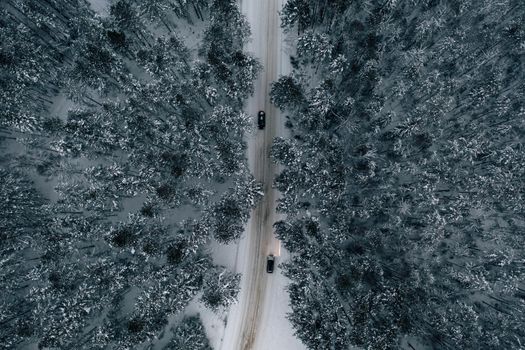Aerial view of snowy road with cars, winter forest