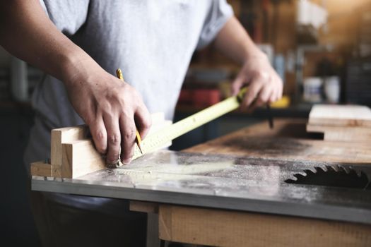 do-it-yourself concept Craftsmen use a tape measure to assemble wooden pieces to make wooden tables for customers.
