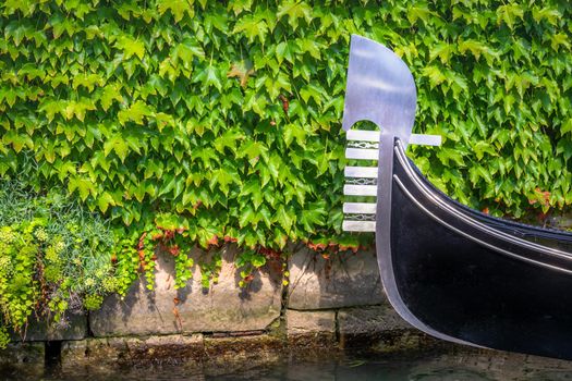 One gondola anchored in front of a green wall in Venice, Italy