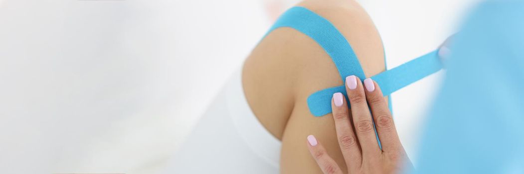 Physiotherapist put kinesiology blue tape on patient knee