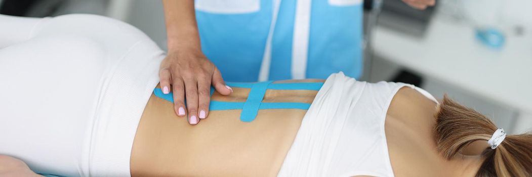 Doctor hold scan of woman back and correct kinesiology tape on females body