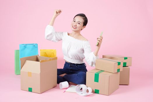 Asian woman, attractive and young, sitting on floor with A lot of parcels and is happy to business success