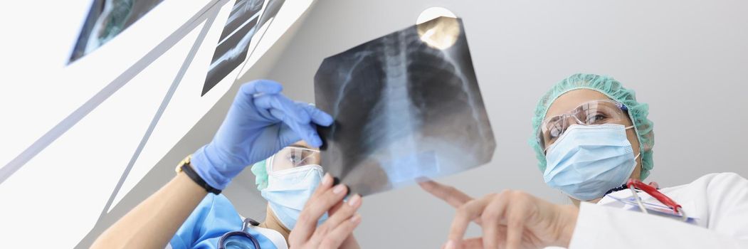 Doctors in medical gowns examine x ray of patient lungs in clinic