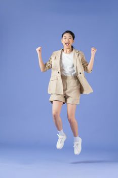 Energetic young asian woman jumping isolated on purple studio background. Excited female celebrating win