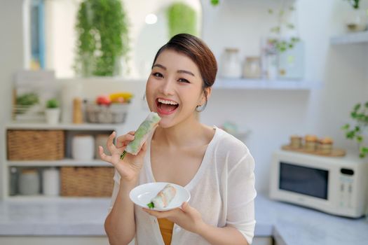 Asian woman eating tasty traditional spring rolls