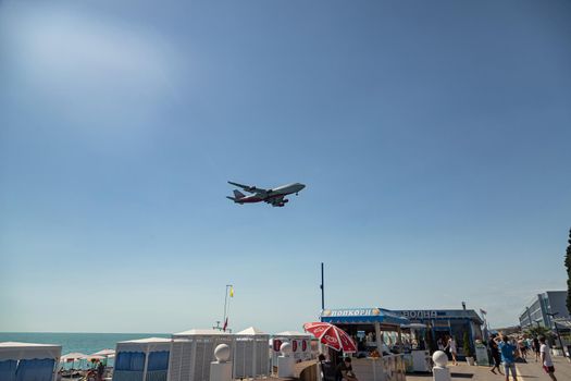 Boeing 747 of Rossiya Airlines lands at Adler Airport from the sea, above the beach with tourists