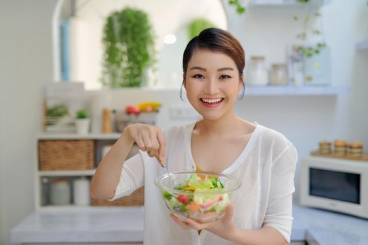 young Asian woman eating salad vegetable in diet concept