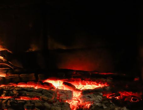 Hot coals of burned wood in the fireplace on a black background. Space for copy, text, your words. Horizontal