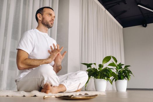 Close-up of a man in white sportswear doing yoga in a fitness room with a balgovon. the concept of a healthy lifestyle