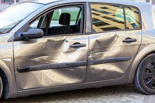Damaged car with a scratches and dent on door, dints on auto after an road accident,