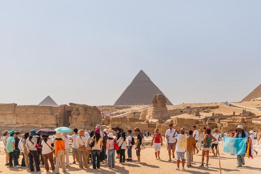 CAIRO, EGYPT - September 11, 2008. Groups of tourists on excursion near Statue of Sphinx and Great Pyramid of Giza.