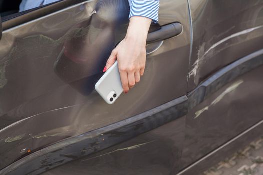 mobile phone and damaged car. woman holding mobile phone.