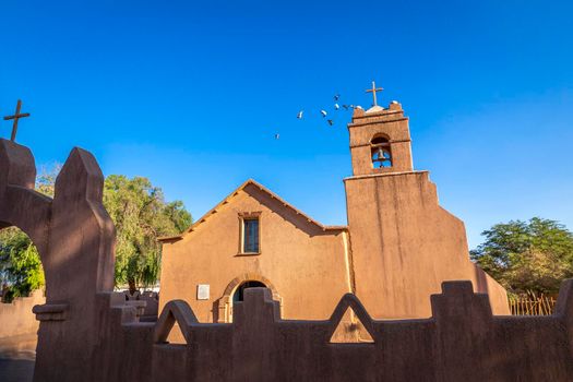 Doves flying above San Pedro de Atacama Church at sunny day, Chile