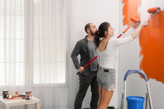 Couple painting wall with orange paint