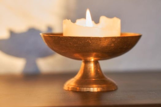Elegant and decorative lit candle on a table at home. Beautiful house decorations used for aroma, good scent and to brighten up a dark room. Candles represent light, illumination, and purification