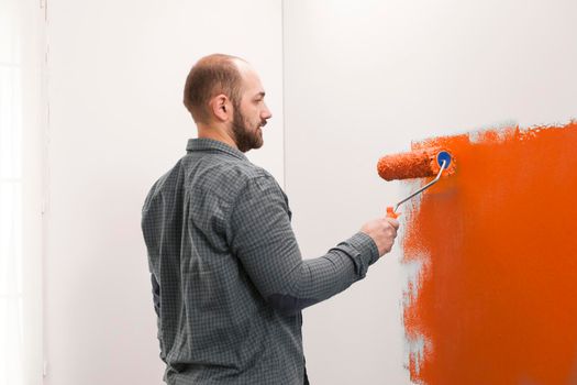 Male painter doing housework with orange paint