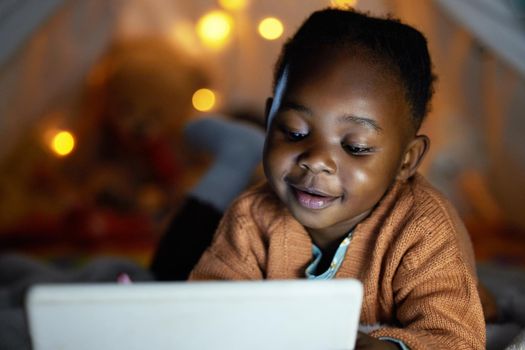 Fun stories make bedtime even better. an adorable little girl using a digital tablet during bedtime at home.