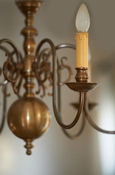 Closeup of a vintage brass chandelier hanging as decoration in a foyer, entrance hall or dinning room during a blackout. Golden candle like lighting decor for a royal victorian style interior design