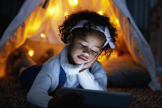 So tired but I cant switch off. an adorable little girl using a digital tablet during bedtime at home.