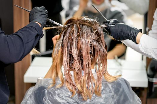 Hairdresser's hands coloring female hair