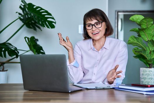 Mature woman using laptop for video call, virtual meeting