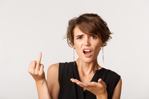 Woman complaining, looking confused and showing finger without wedding ring, standing over white background