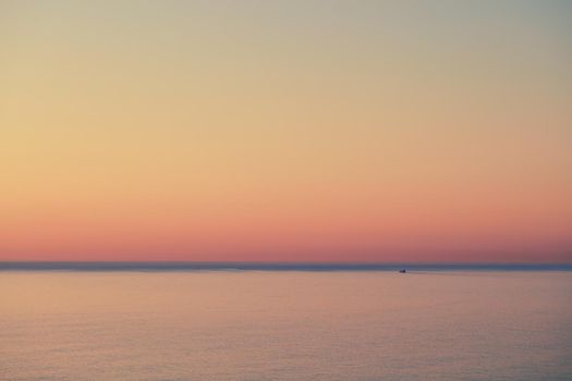 Seascape of a beautiful golden sunset with copy space. Sun setting on the horizon of a calm ocean at dusk or twilight. The calm and tranquil ocean or sea in the evening with bright sky copyspace