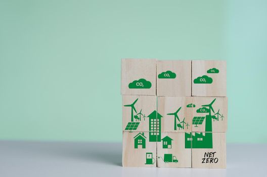 Wooden cubes with net zero and carbon neutral green factory icon symbol background and copy space.