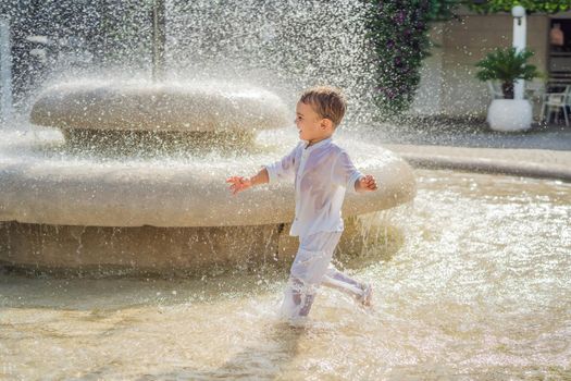 Happy boy plays in the street fountain
