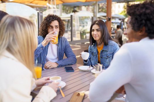 Multi-ethnic group of friends having a drink together in an outdoor bar.