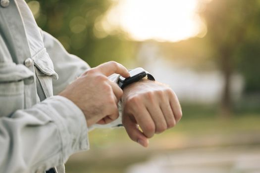 Man's hand touching a smartwatch. Close up shot of male's hand uses of wearable smart watch at outdoor in sunset. Smart watch. Smart watch on a man's hand outdoor