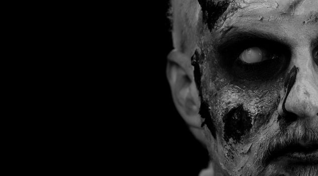 Close-up face of sinister man with horrible scary Halloween zombie makeup looking creepy at camera