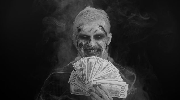Scary sinister Halloween zombie wounded undead man with money dollar cash banknotes smiles terribly