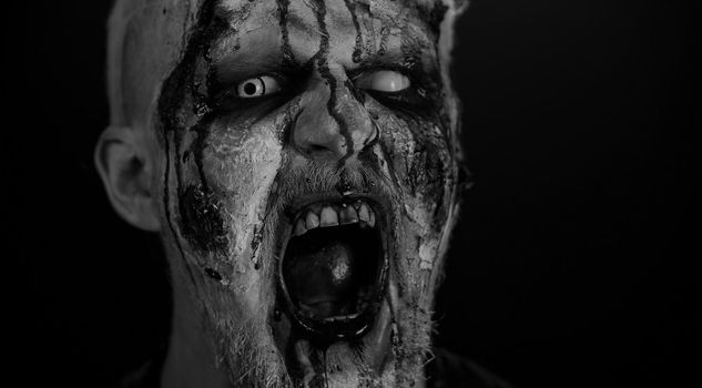 Zombie man face makeup with wounds scars and white contact lenses blood flows and drips on face