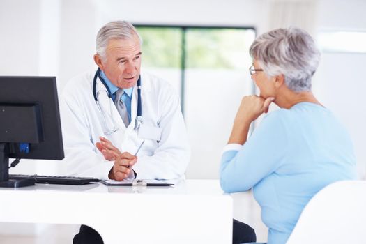 Doctor discussing medical report with patient. Confident mature doctor discussing medical report with female patient.